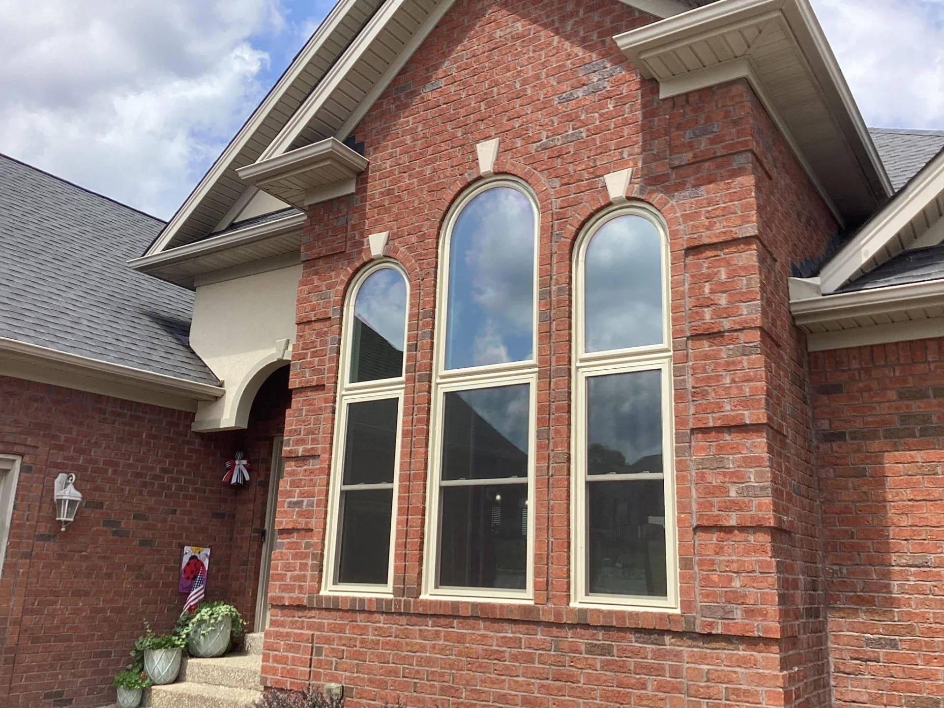 A brick home with striking arched replacement windows installed by Windows Plus